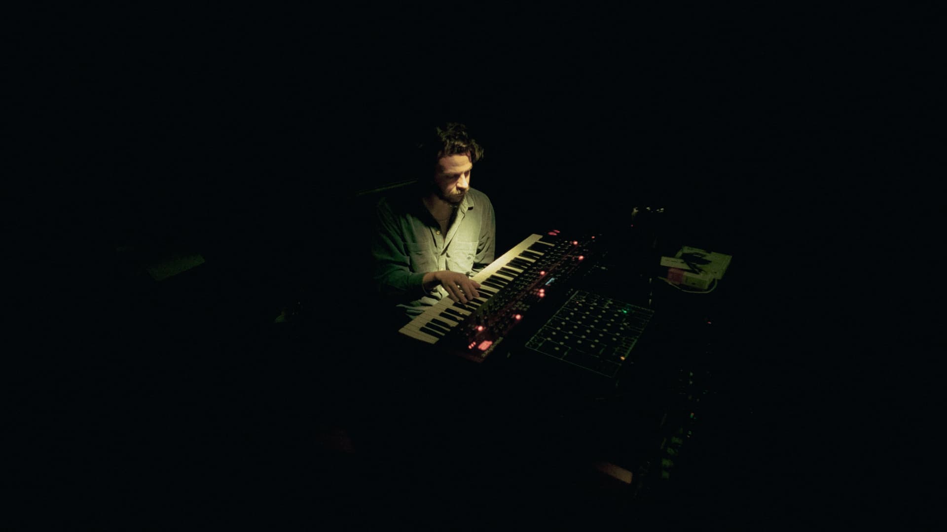 Andy Rivero tocando un sintetizador en la oscuridad